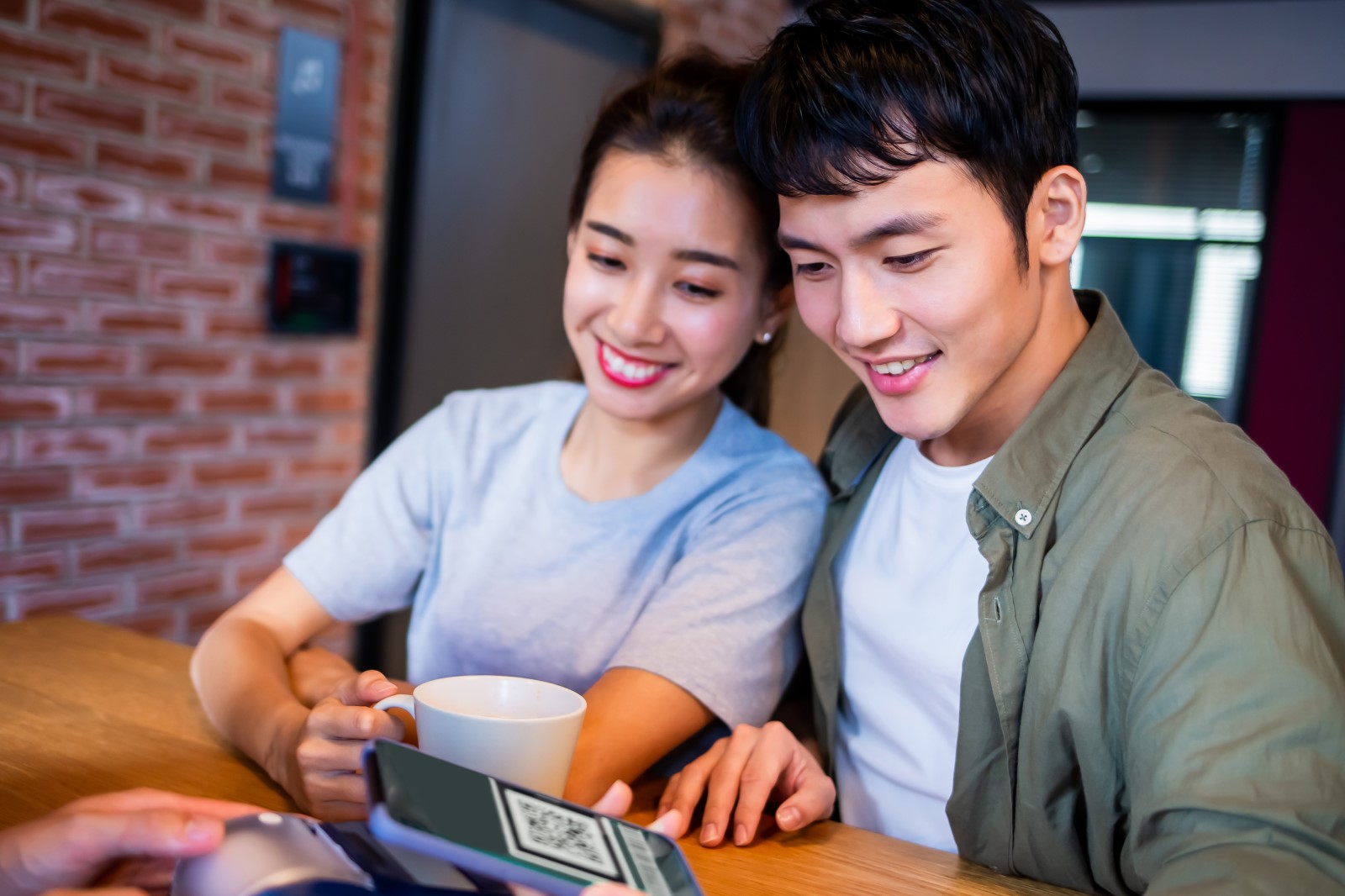Imagem mostra casal pagando a conta do café com Qr Code de Pix em maquininha