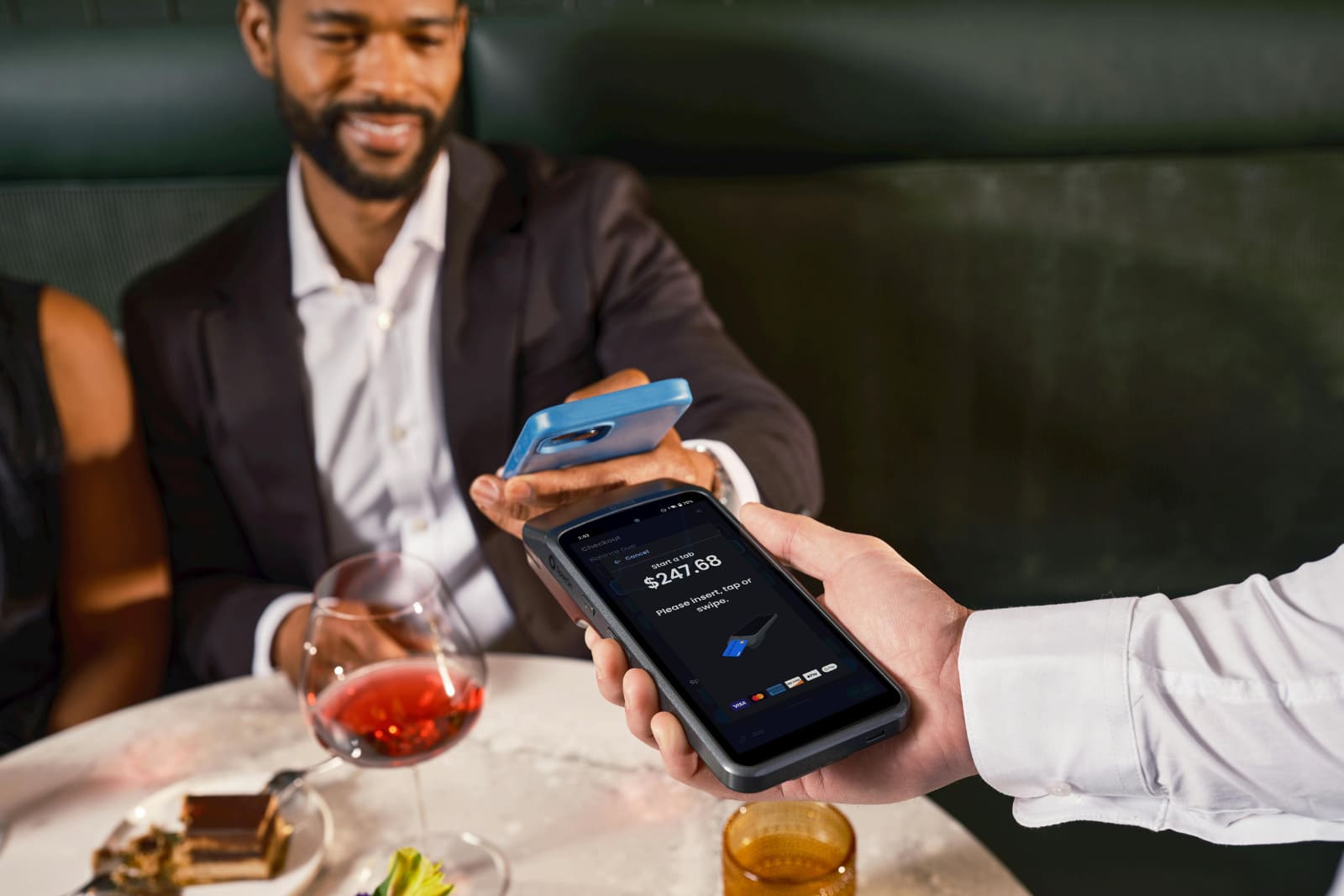 Garçom recebendo pagamento com vale-refeição usando um celular com pagamento Tap on Phone.